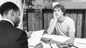 Man feeling stressed during a job interview while employer reviews documents